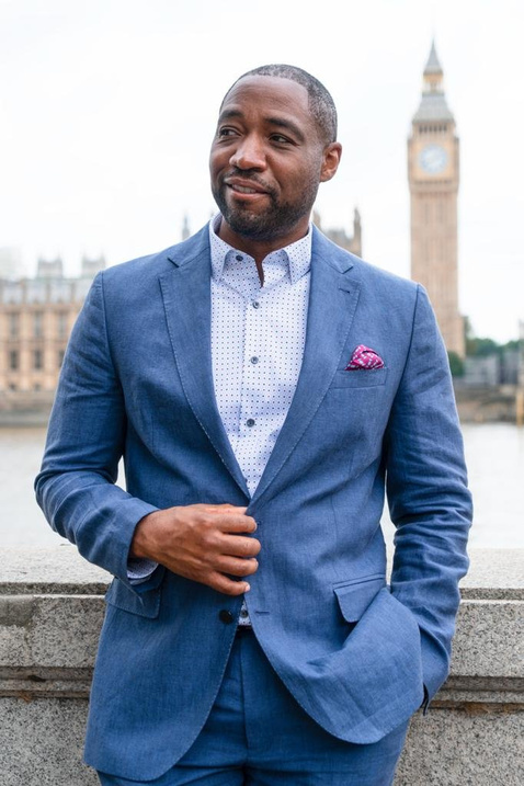 a person in a blue suit and white shirt standing in front of the big ben