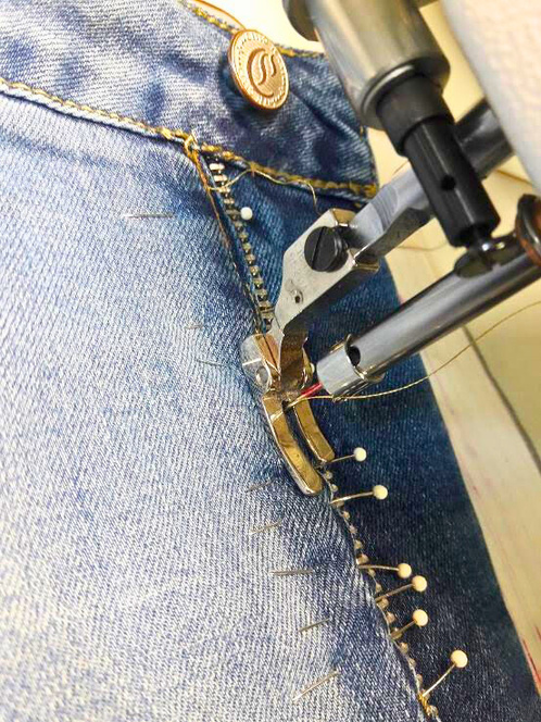 a pair of jeans being sewn with a sewing machine