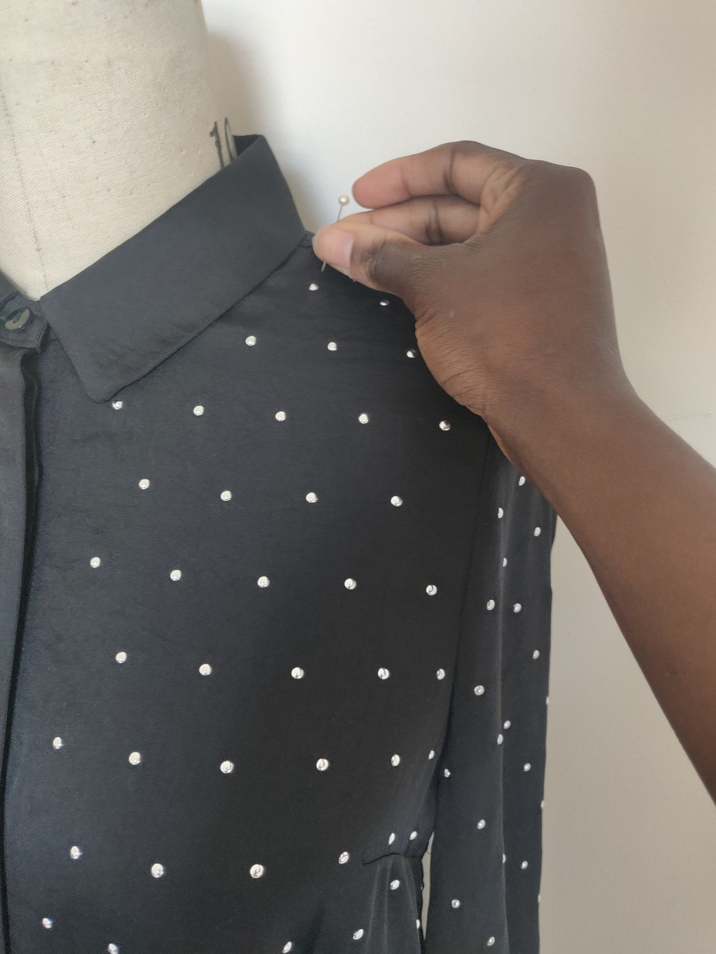 a person is adjusting a polka dot shirt on a mannequin